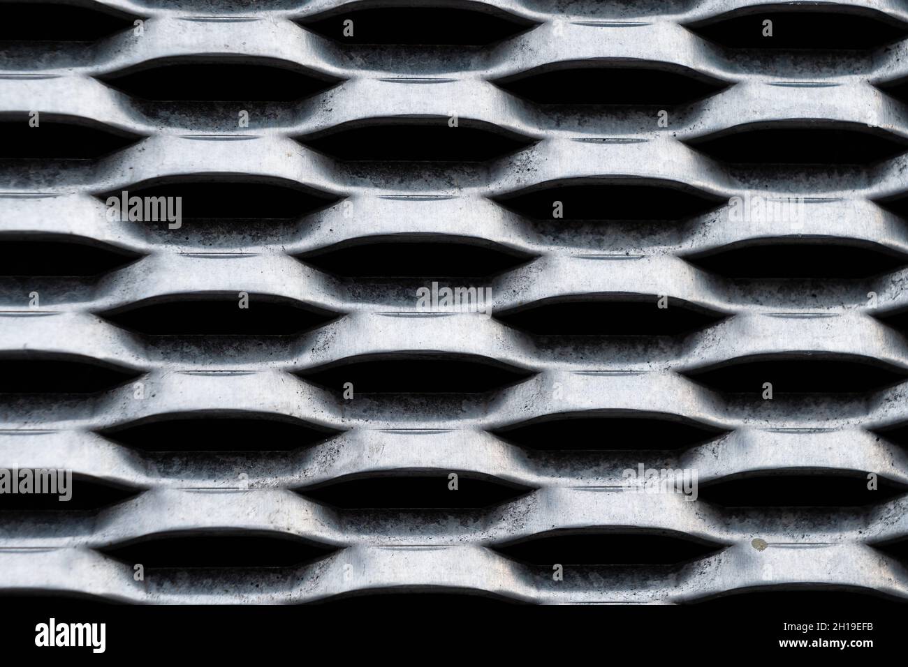 Sfondo di una griglia industriale in metallo grigio sulla facciata di una casa Foto Stock