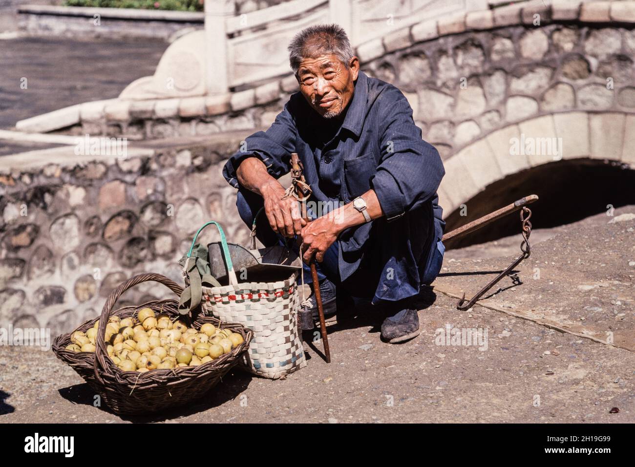 Un venditore con la sua bilancia che vende prodotti in un mercato agricolo a Mutianyu, Cina. Foto Stock