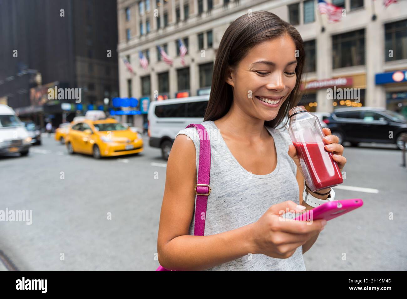 Città urbana moderna ragazza asiatica utilizzando l'app telefono bere frutta sana succo di verdura frullato camminare su Manhattan Street New York City, USA. Felice Foto Stock