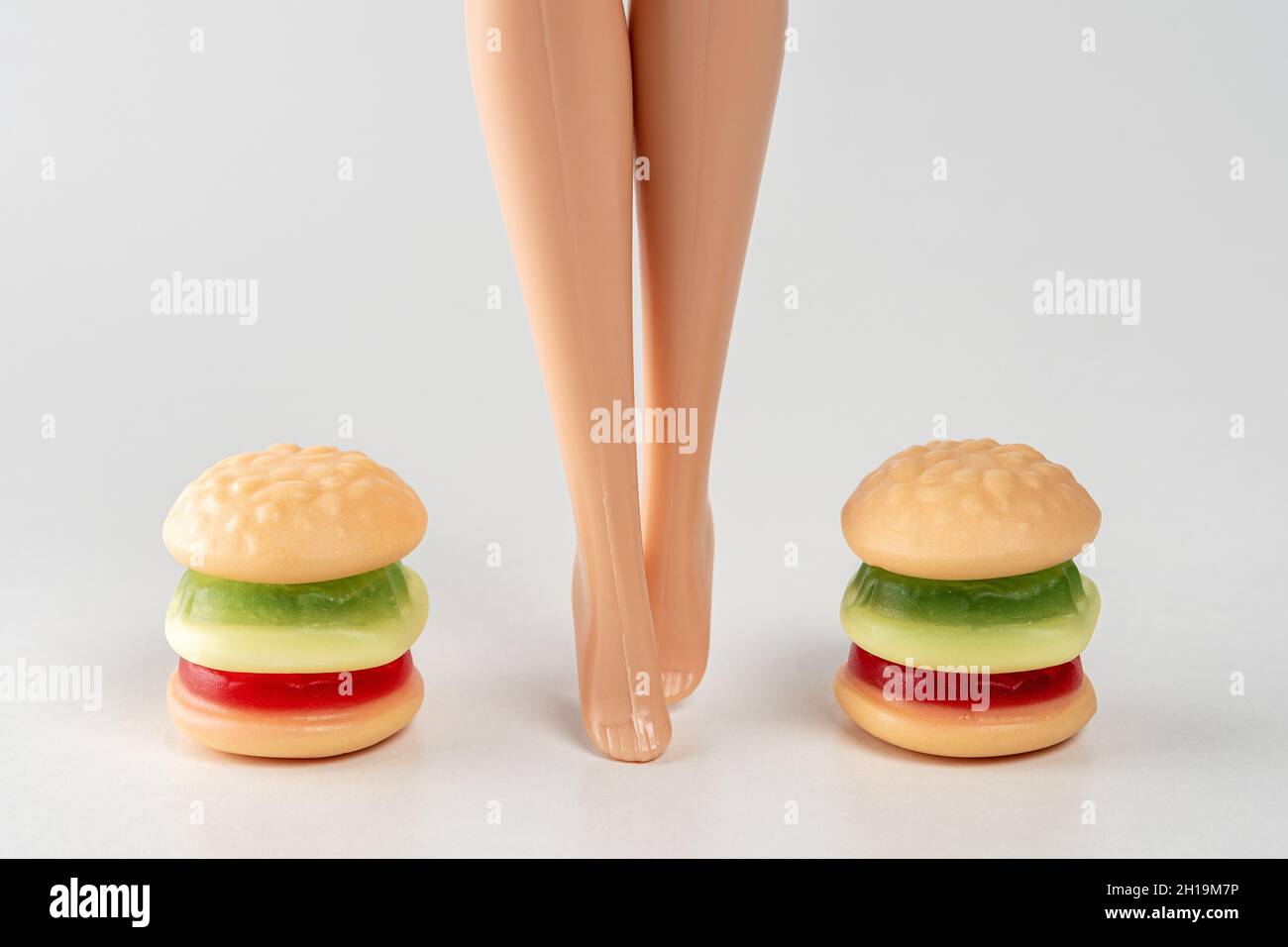 Hamburger di caramelle colorate con le gambe di bambola. Concetto minimo di cibo fitness. Foto Stock