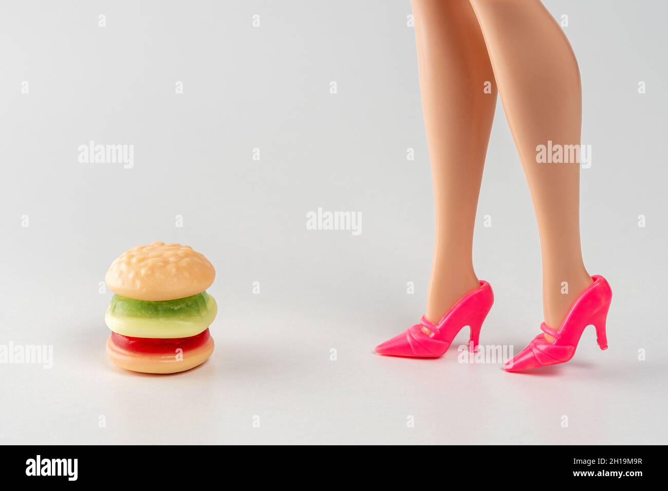 Hamburger di caramelle colorate con le gambe di bambola. Concetto minimo di cibo fitness. Foto Stock