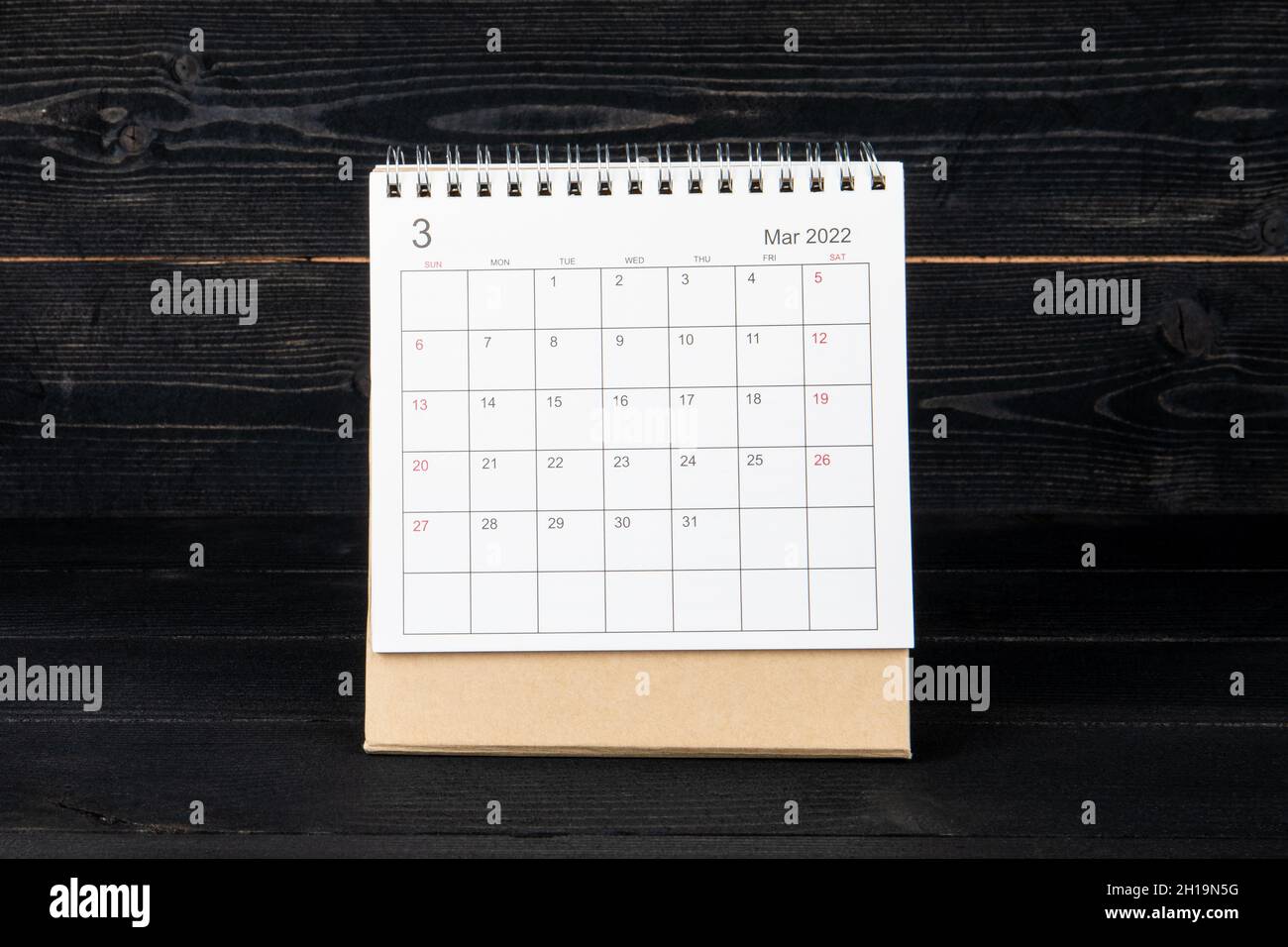 Marzo 2022. Calendario e pianificatore su sfondo di tessitura di legno nero. Foto Stock