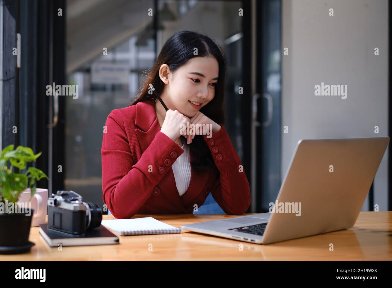 Donna d'affari che ha una videochiamata sul laptop mentre discute con il socio di affari durante il lavoro dalla sede. Foto Stock