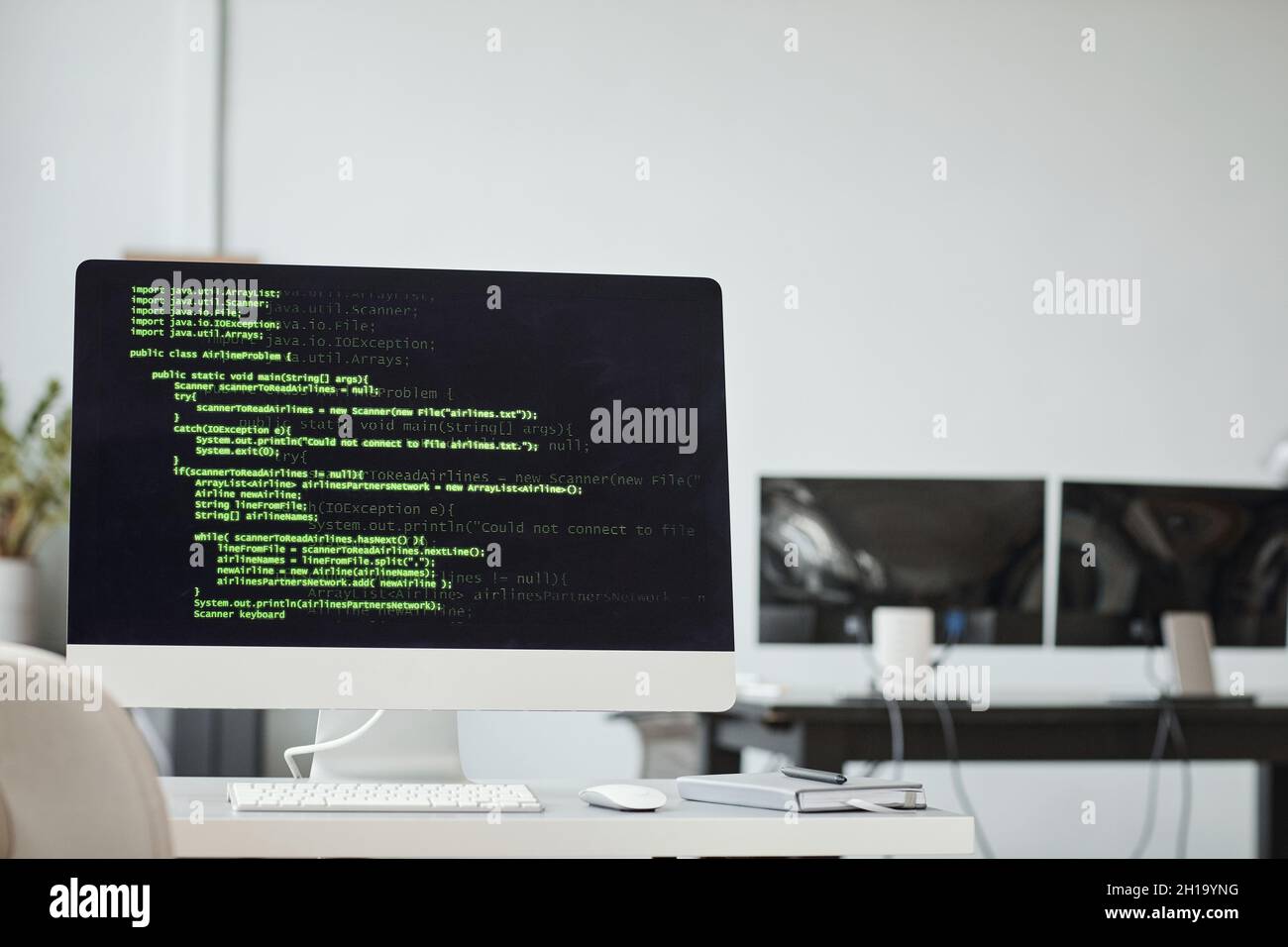 Immagine di sfondo dello schermo del PC con righe di codice verdi negli interni dell'ufficio di sviluppo del software, spazio di copia Foto Stock