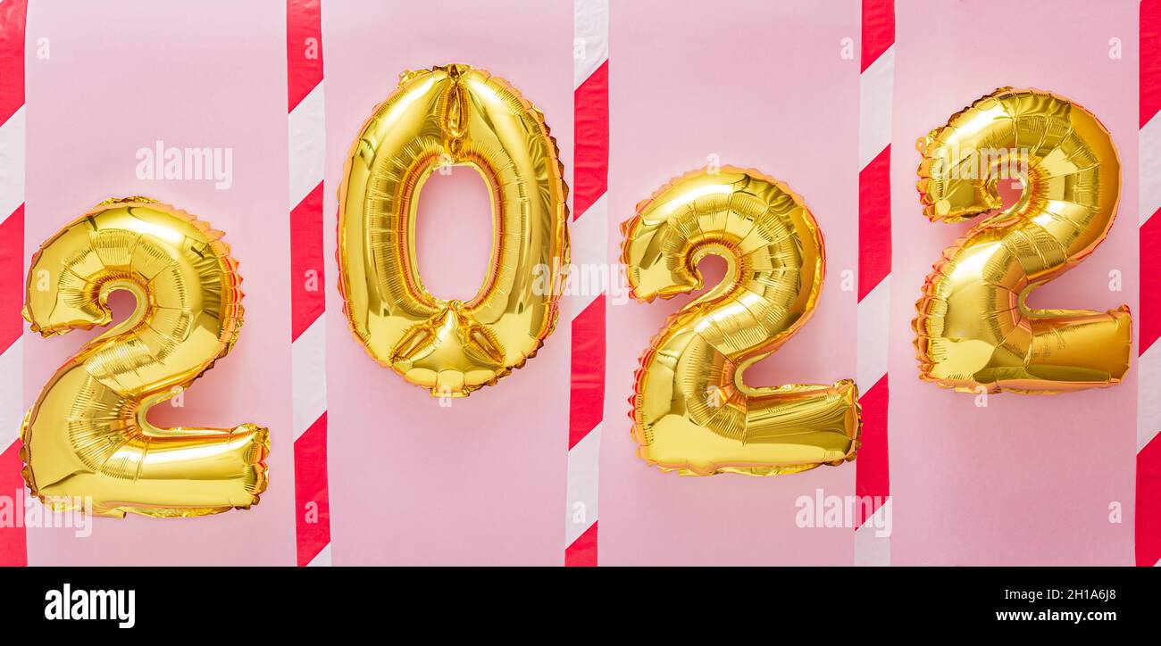 2022 palloncini d'oro. 2022 in linea con nastro di avvertimento su sfondo rosa per mantenere la distanza sociale durante il covid 19 coronavirus Lockdown Nuova norma Foto Stock