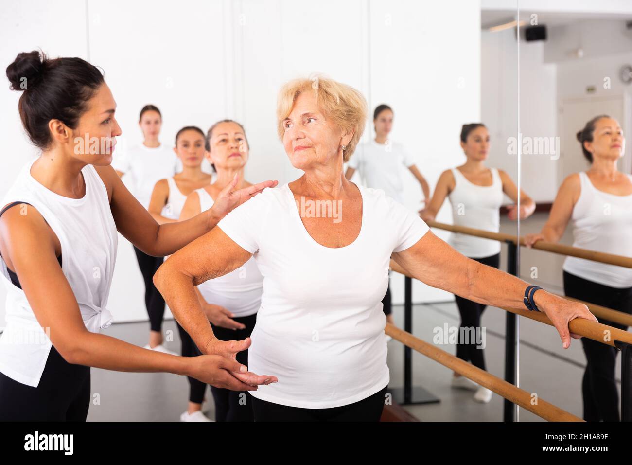 Varie donne anziane che esercitano il balletto si muove con il formatore Foto Stock