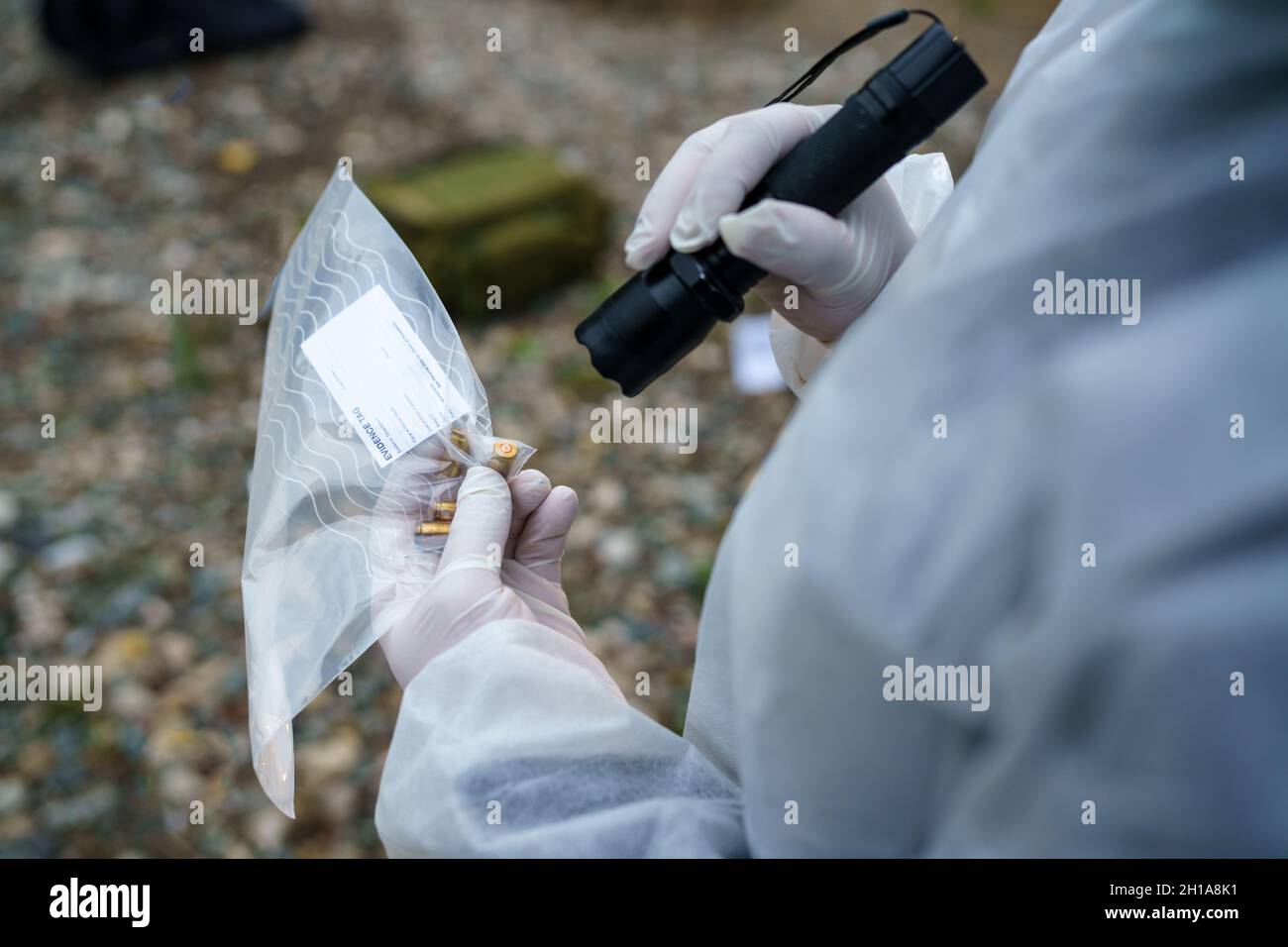 Primo piano vista posteriore sulle mani di un uomo sconosciuto polizia forense che raccoglie le prove nel sacchetto di plastica alla scena del crimine Foto Stock