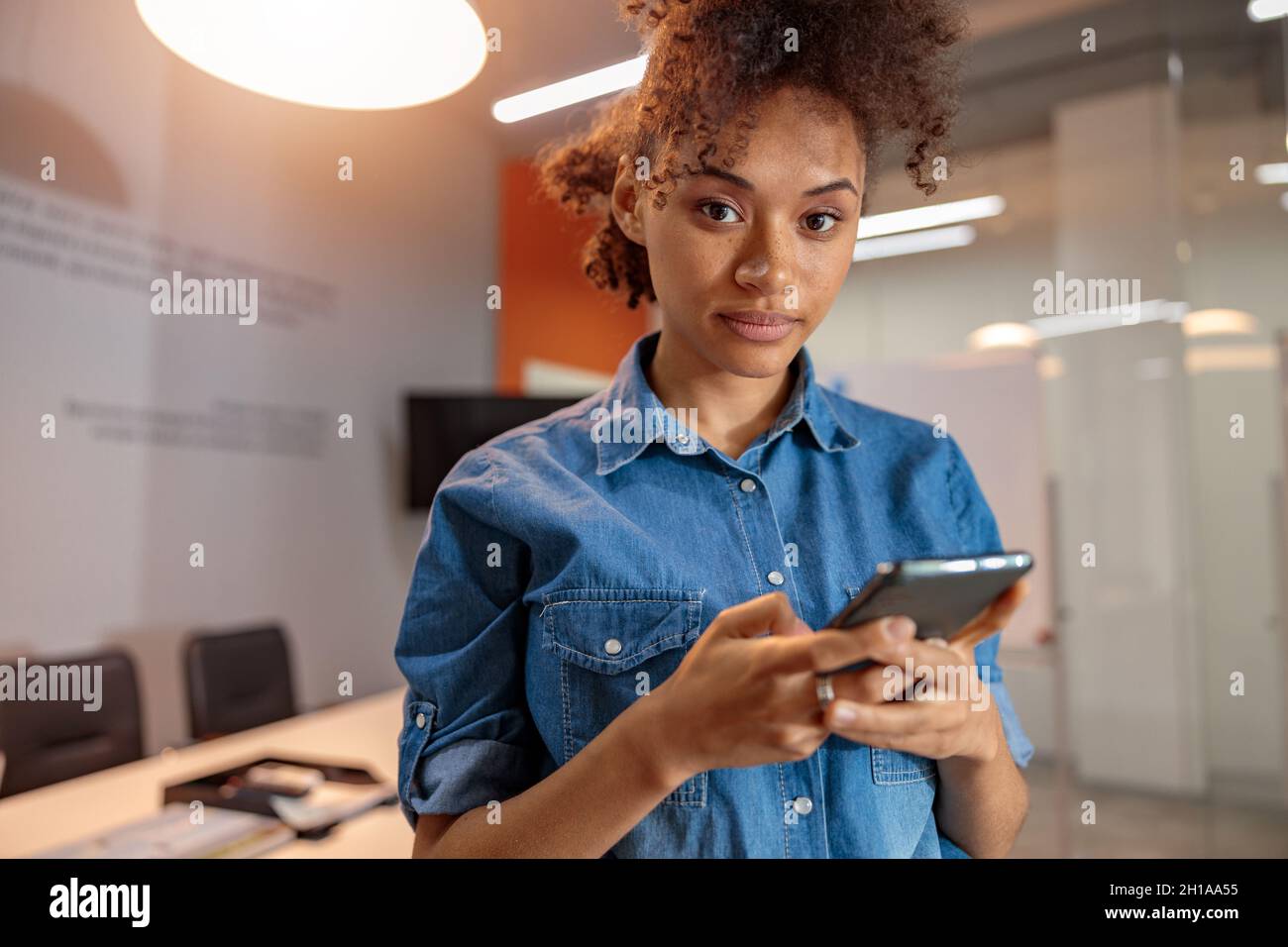 Datore di lavoro multietnico femminile che tiene in mano lo smartphone Foto Stock