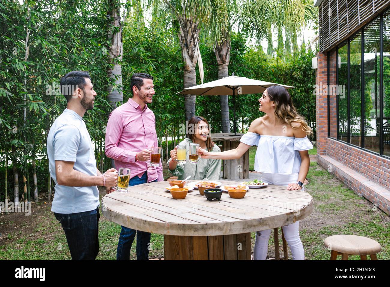 Gruppo di giovani amici latini incontro per birra, bevande michelada e cibo messicano preparare un toast nella terrazza del ristorante in Messico America Latina Foto Stock