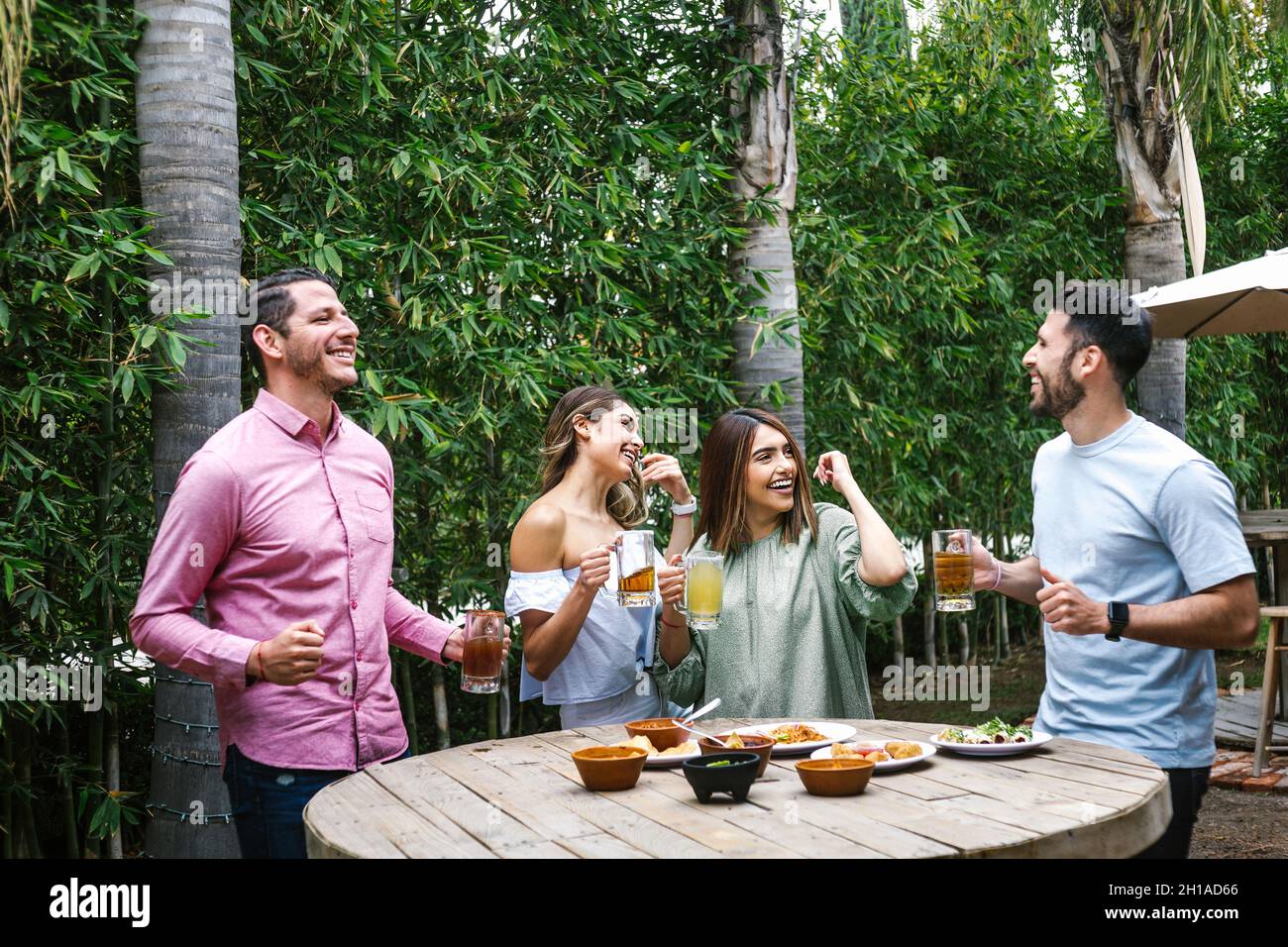 Gruppo di giovani amici latini incontro per birra, bevande michelada e cibo messicano preparare un toast nella terrazza del ristorante in Messico America Latina Foto Stock