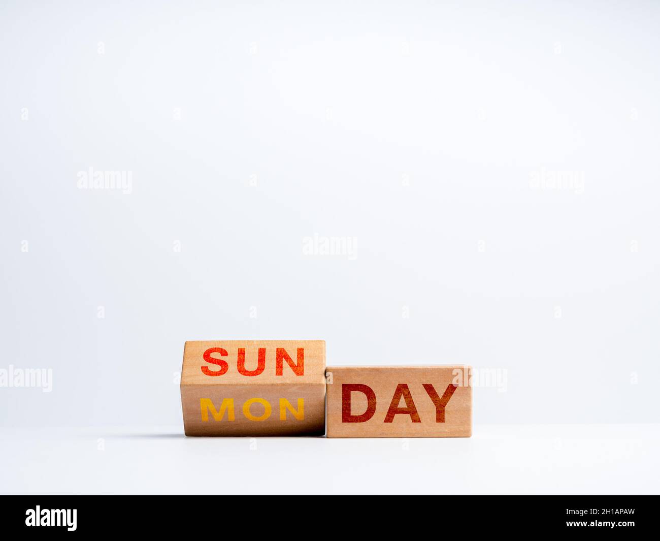 Passaggio al primo giorno lavorativo della settimana. Flipping blocchi di cubo di legno per cambiare le parole, giorni da Domenica a Lunedi sulla scrivania su backgroun bianco Foto Stock