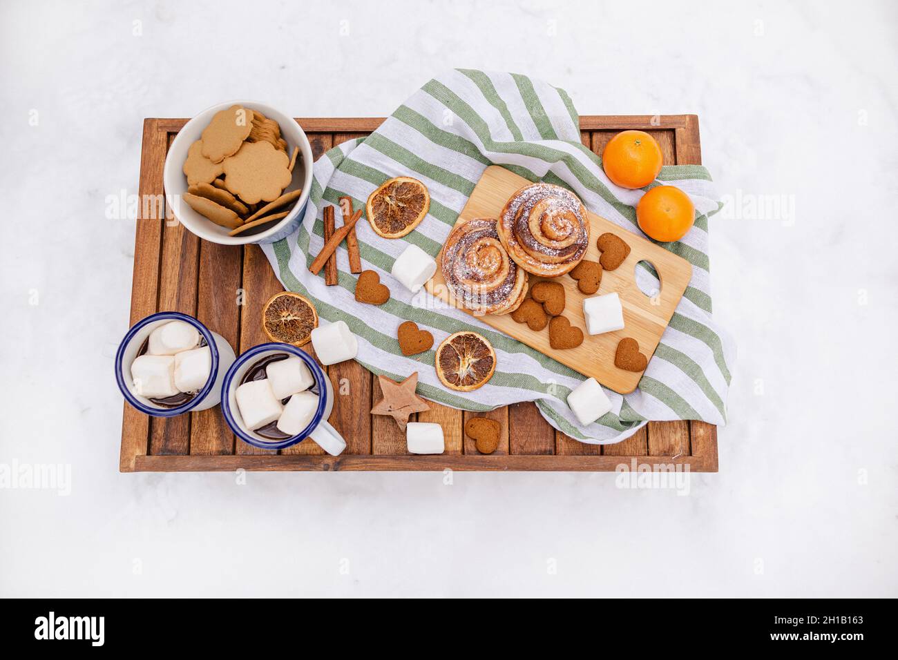 Tavolo da picnic invernale in legno con tazze da tè, marshmallows, arance, biscotti. Tavolo di Natale sulla neve Foto Stock