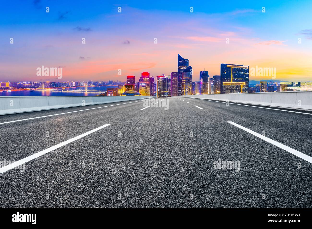 Strada asfaltata e moderno skyline della città con edifici a Hangzhou di notte. Foto Stock