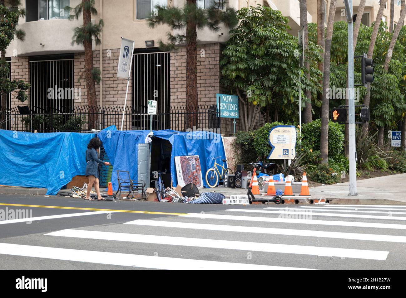 Los Angeles, CA USA - Settembre 28 2021: Accampamento senza casa e mucchi di rifiuti accanto ad un edificio di appartamenti con un cartello di affitto Foto Stock
