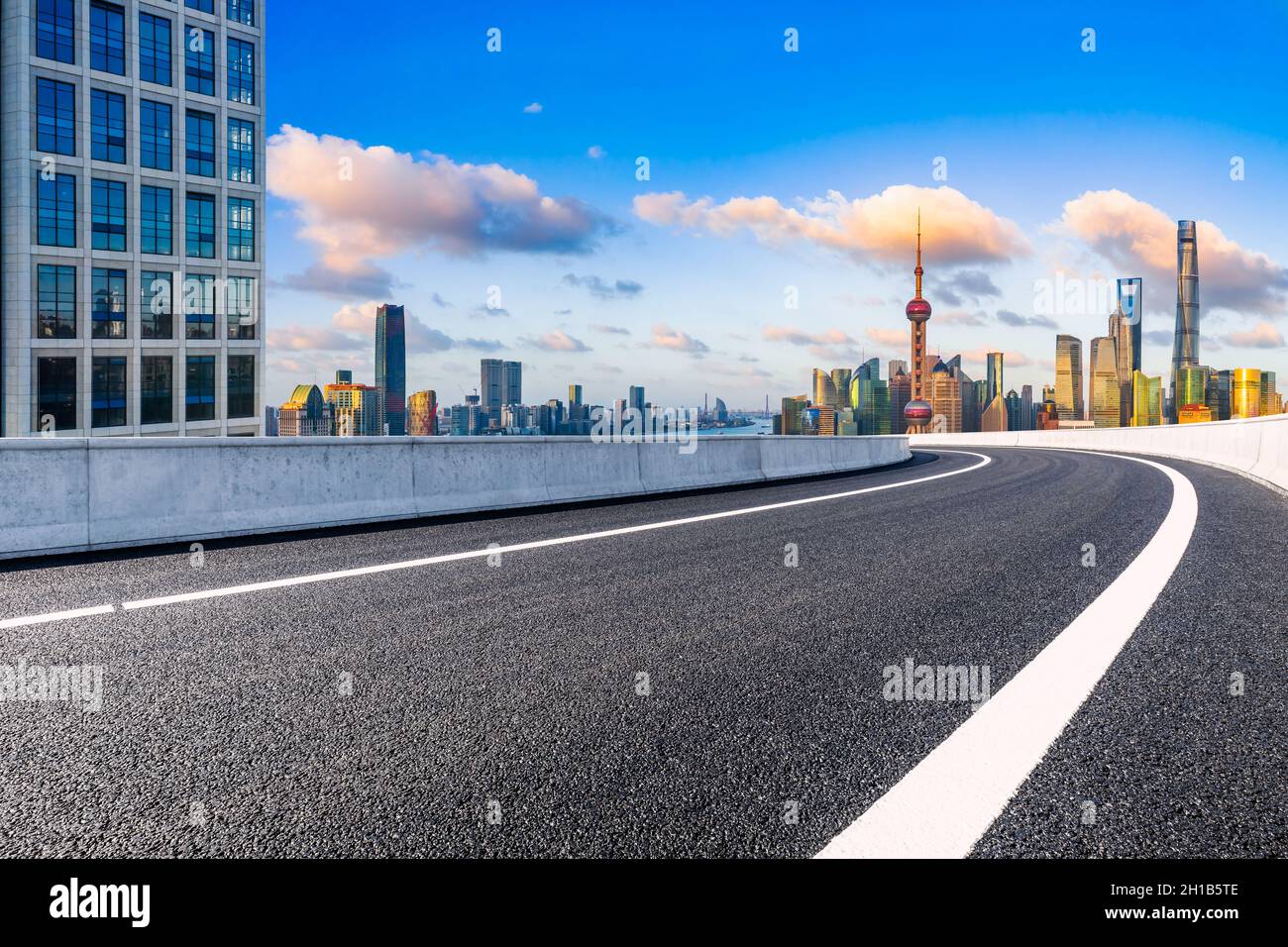 Strada asfaltata vuota e skyline di Shanghai con edifici al tramonto. Foto Stock