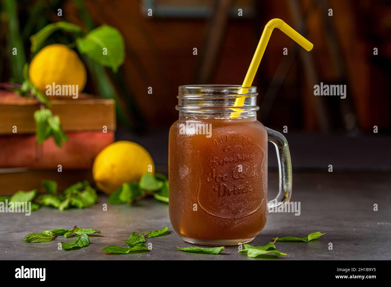 Rinfrescante tè freddo al limone in una tazza di vetro su sfondo scuro Foto Stock
