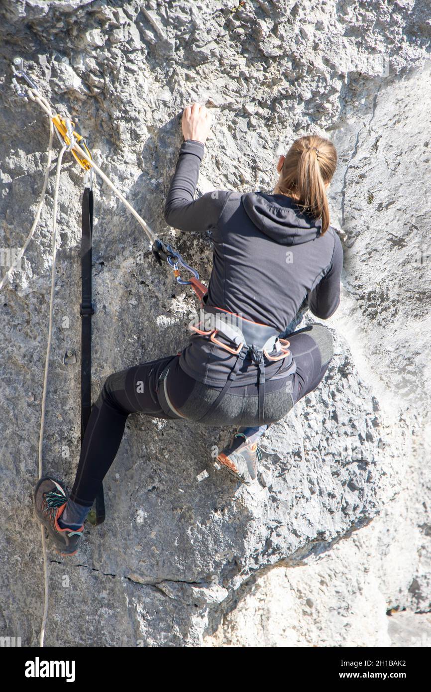 Giovane donna che arrampica parete rocciosa naturale alta Foto Stock