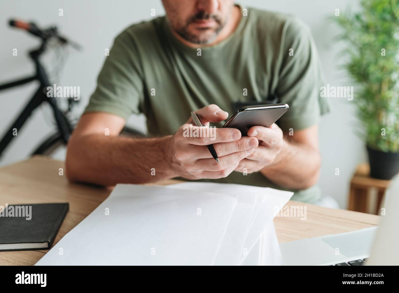 Telecommuter lettura SMS su smartphone mobile in ufficio, fuoco selettivo Foto Stock
