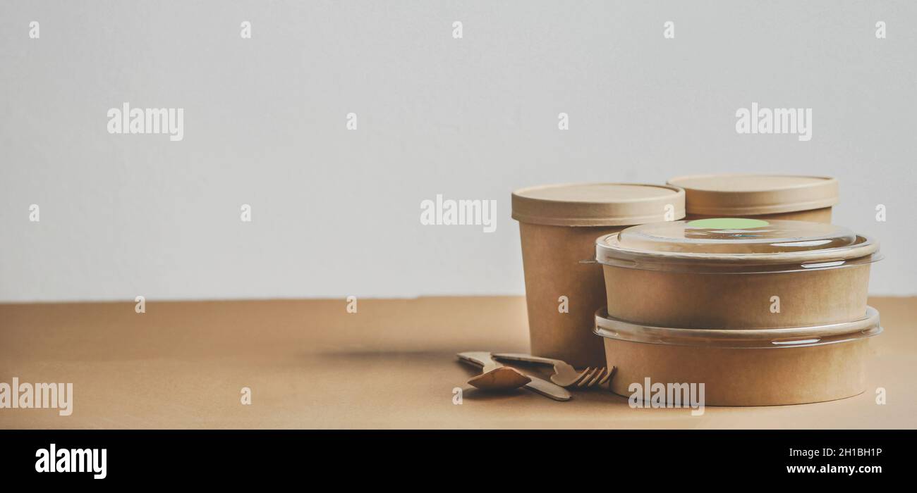 Selezione di contenitori per la consegna di alimenti moderni e sostenibili e posate sul tavolo da cucina su sfondo bianco. Vista frontale con spazio di copia. Banner Foto Stock