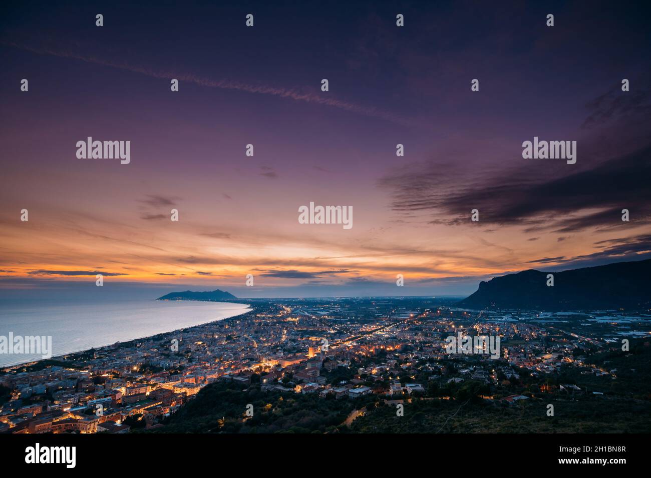 Terracina, Italia. Vista dall'alto skyline città in serata Tramonto. Illuminazioni cittadine Foto Stock