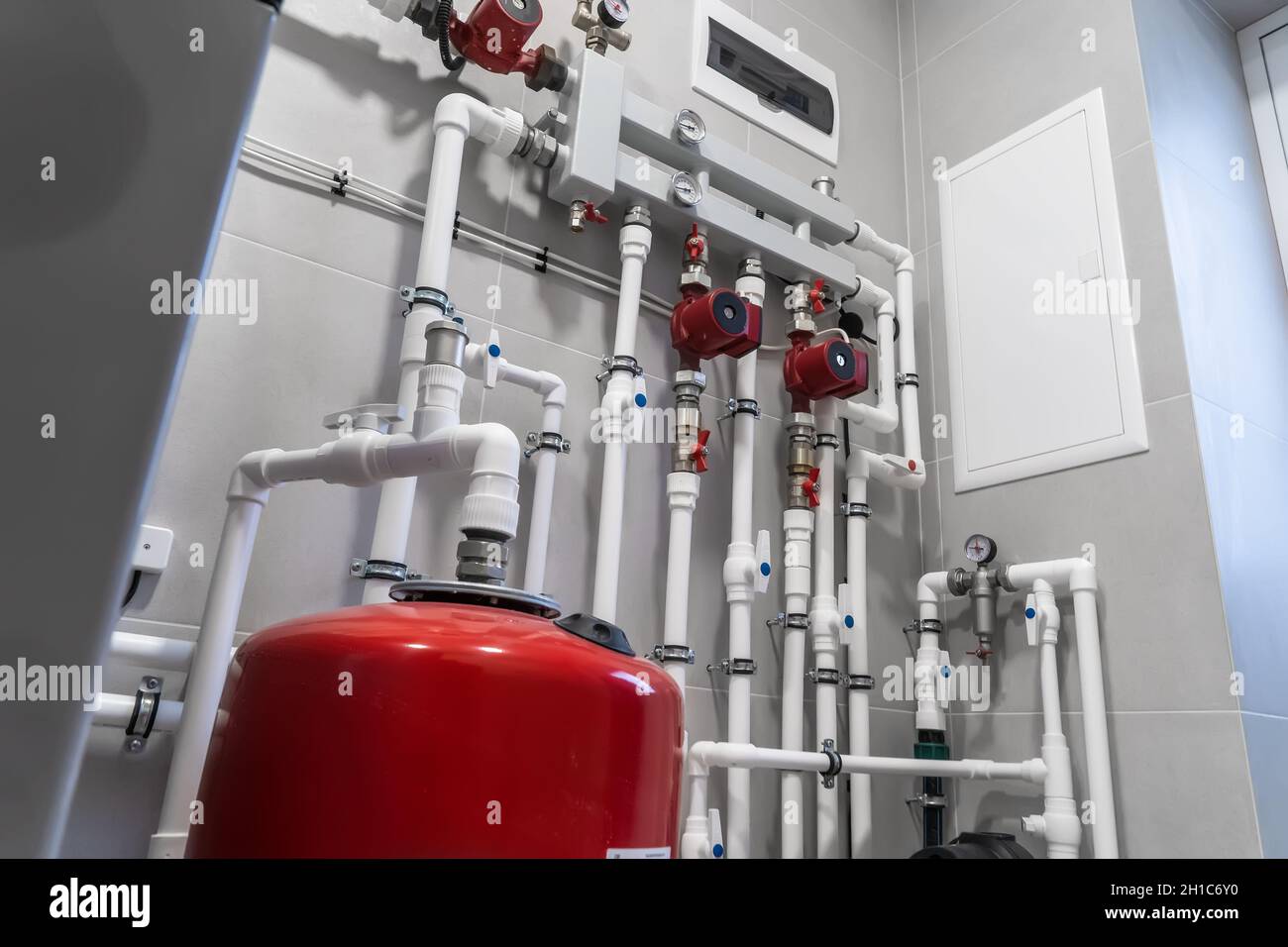 Impianto di riscaldamento casa con moderni tubi in plastica, manometri e tubi in primo piano nel locale caldaie. Foto Stock