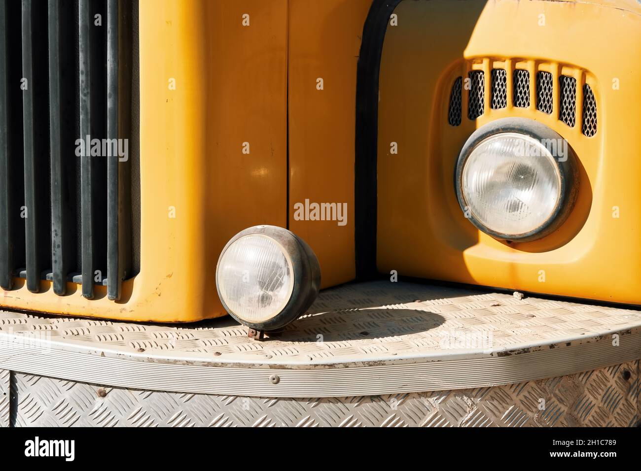 Dettaglio della vista frontale di un veicolo giallo d'epoca con fari rotondi Foto Stock