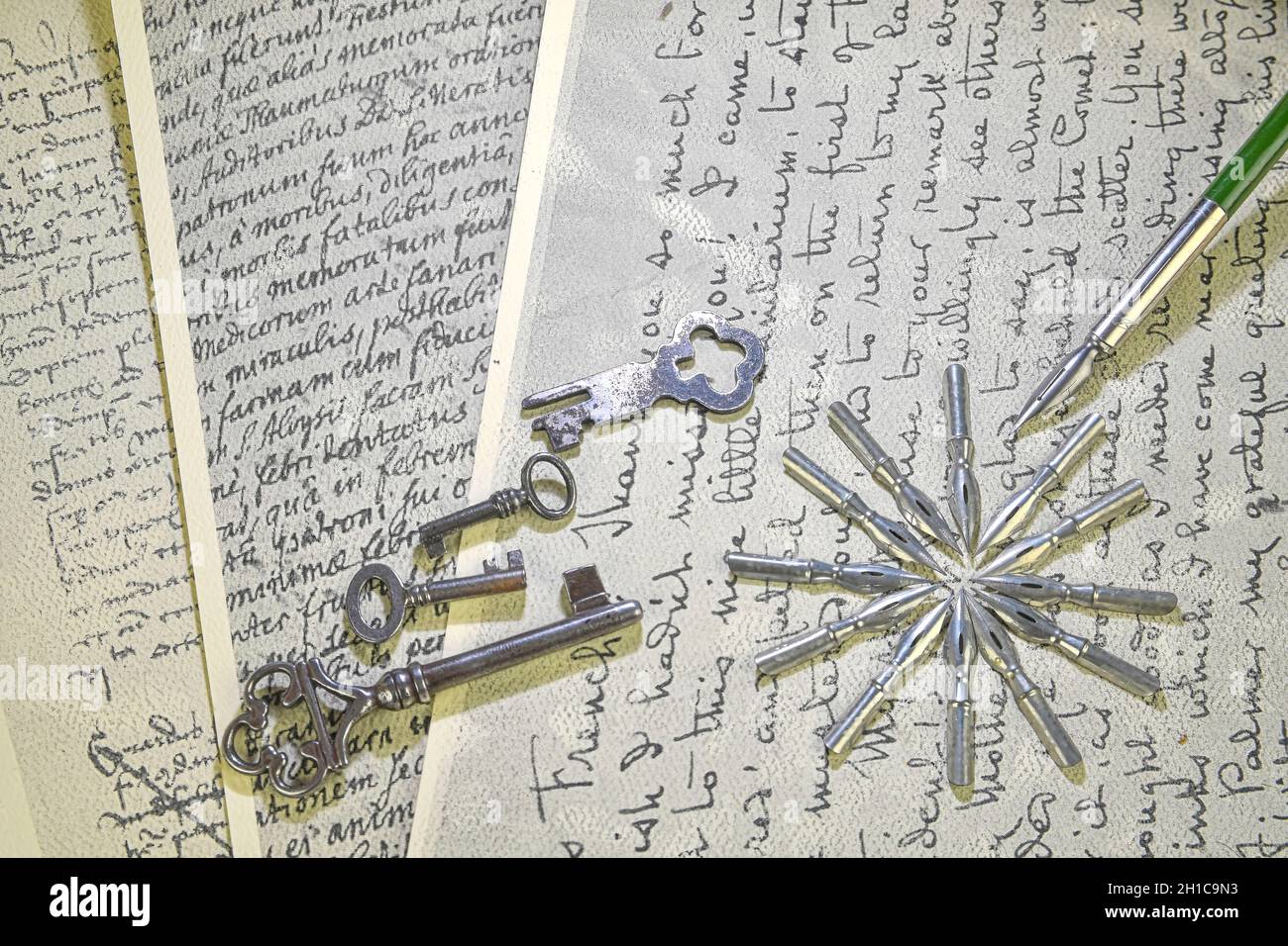 Primo piano degli accessori vintage sulla scrittura a mano vintage. Chiavi, pennini metallici e penna vecchia. Cancelleria d'epoca. Disposizione piatta Foto Stock