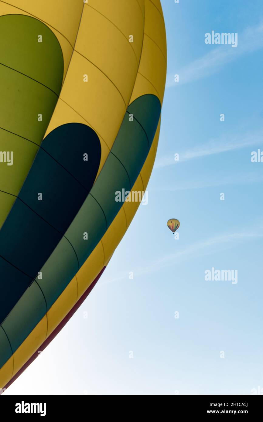 Due palloncini ad aria calda che volano nel cielo blu. Uno in dettaglio e uno lontano. Foto Stock