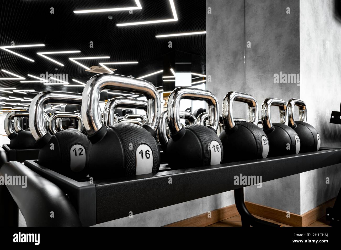 File di manubri in metallo su rack per bodybuilding in palestra Foto Stock