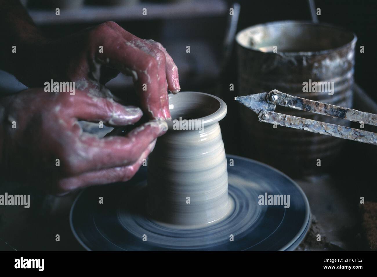 Primo piano delle mani dell'uomo gettando una pentola sulla ruota di un vasaio. Foto Stock