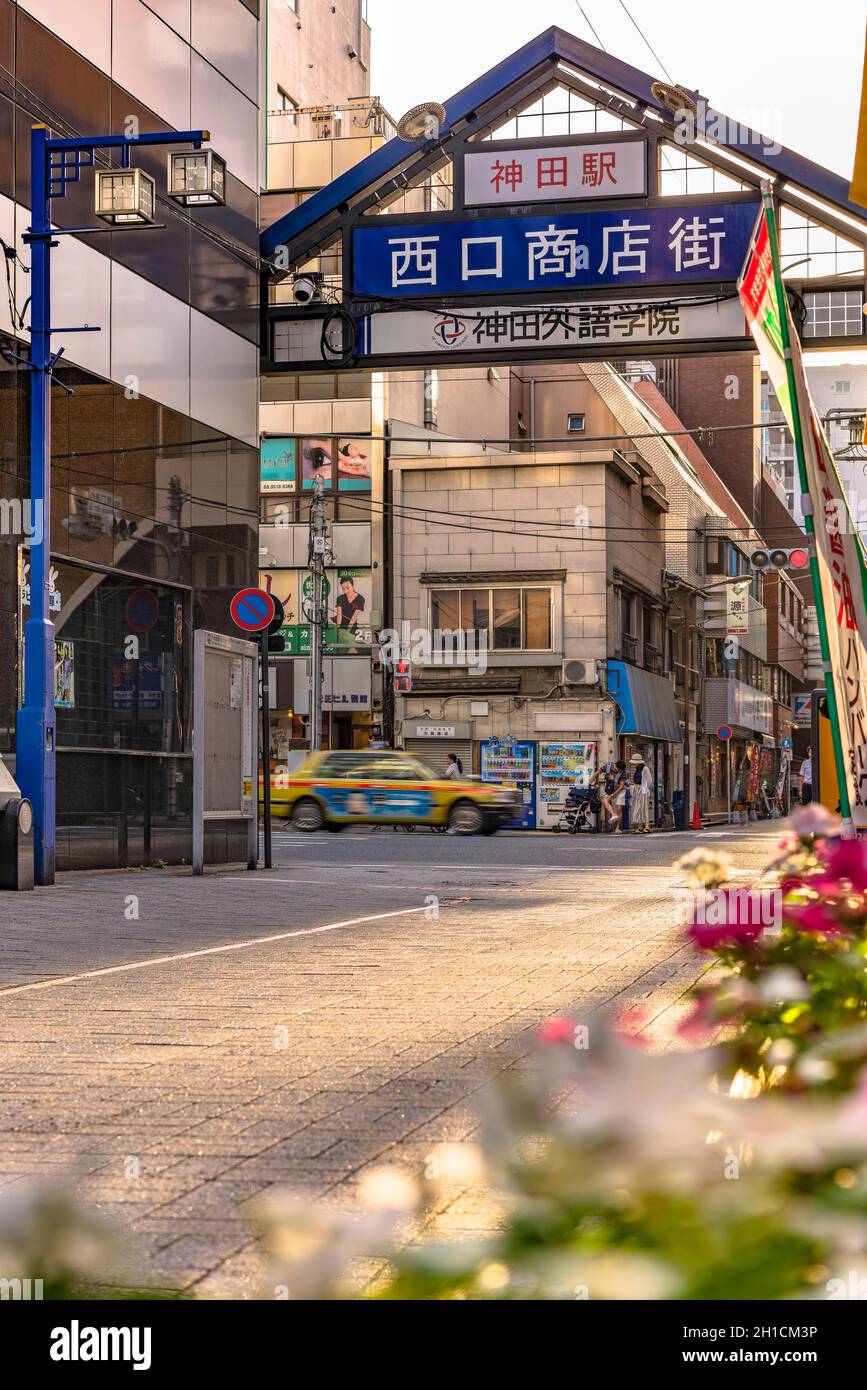Porta d'ingresso in metallo blu della strada dello shopping decorata con fiori dall'uscita ovest della stazione di Kanda sulla linea Yamanote. La strada si estende ov Foto Stock