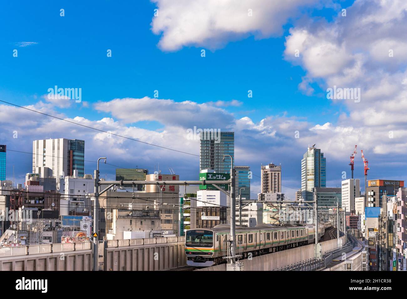 Stazione di kanda dove i treni della linea yamanote passano tra la cima degli edifici del quartiere di Chiyoda sotto il cielo blu di Tokyo. Foto Stock