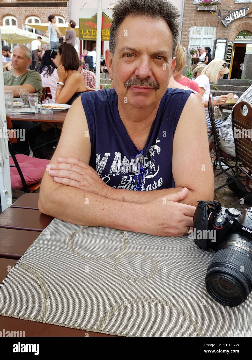 Lüneburg, NIEDERSACHSEN, GERMANIA - JULI 27, 2017: L'uomo è seduto nella birreria all'aperto di un ristorante a Lueneburg con il telefono cellulare in mano. Guardando Foto Stock