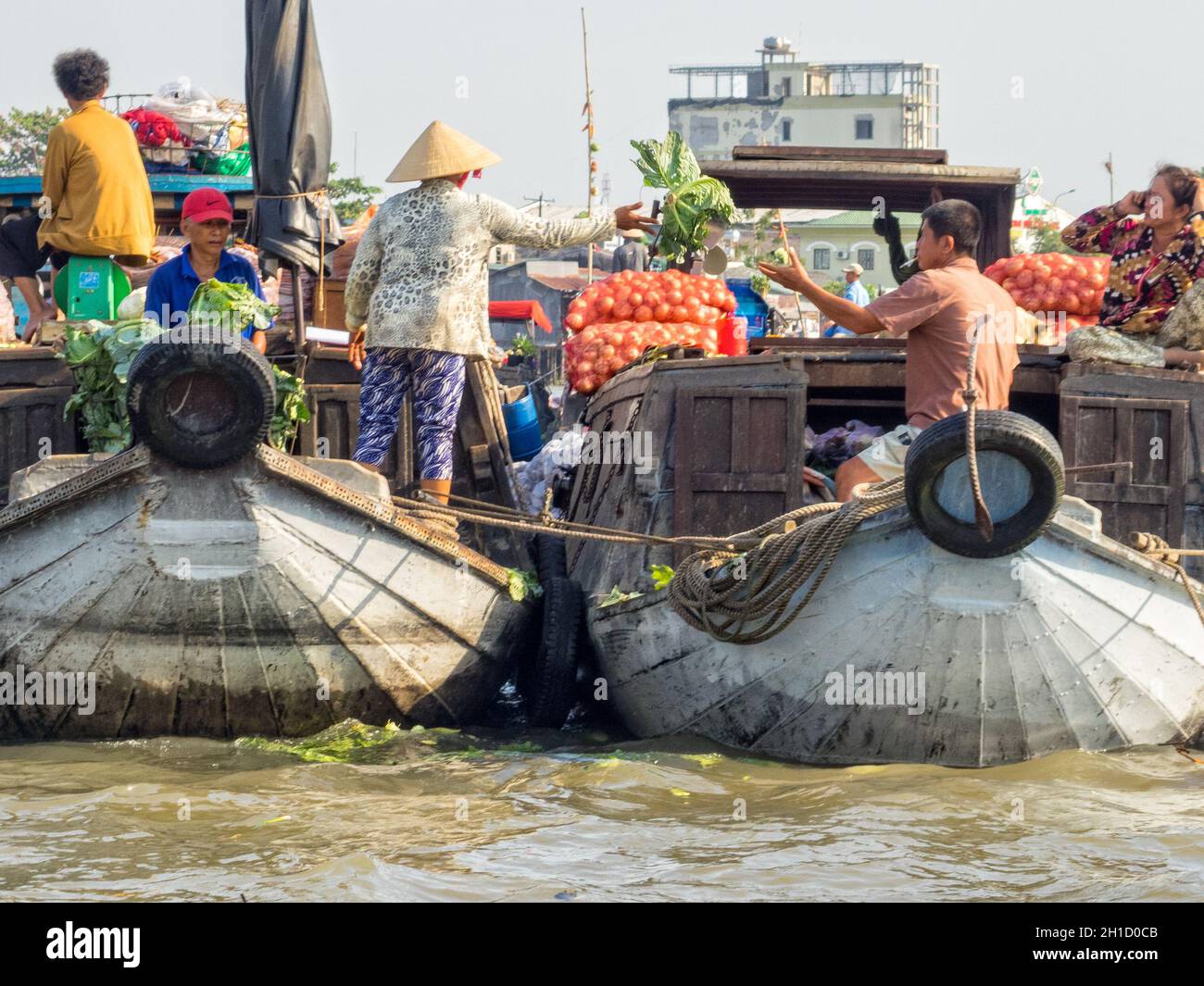 I locali commerciano merci dalle loro barche nel mercato galleggiante sul delta del fiume Mekong - Cai Rang, Vietnam Foto Stock