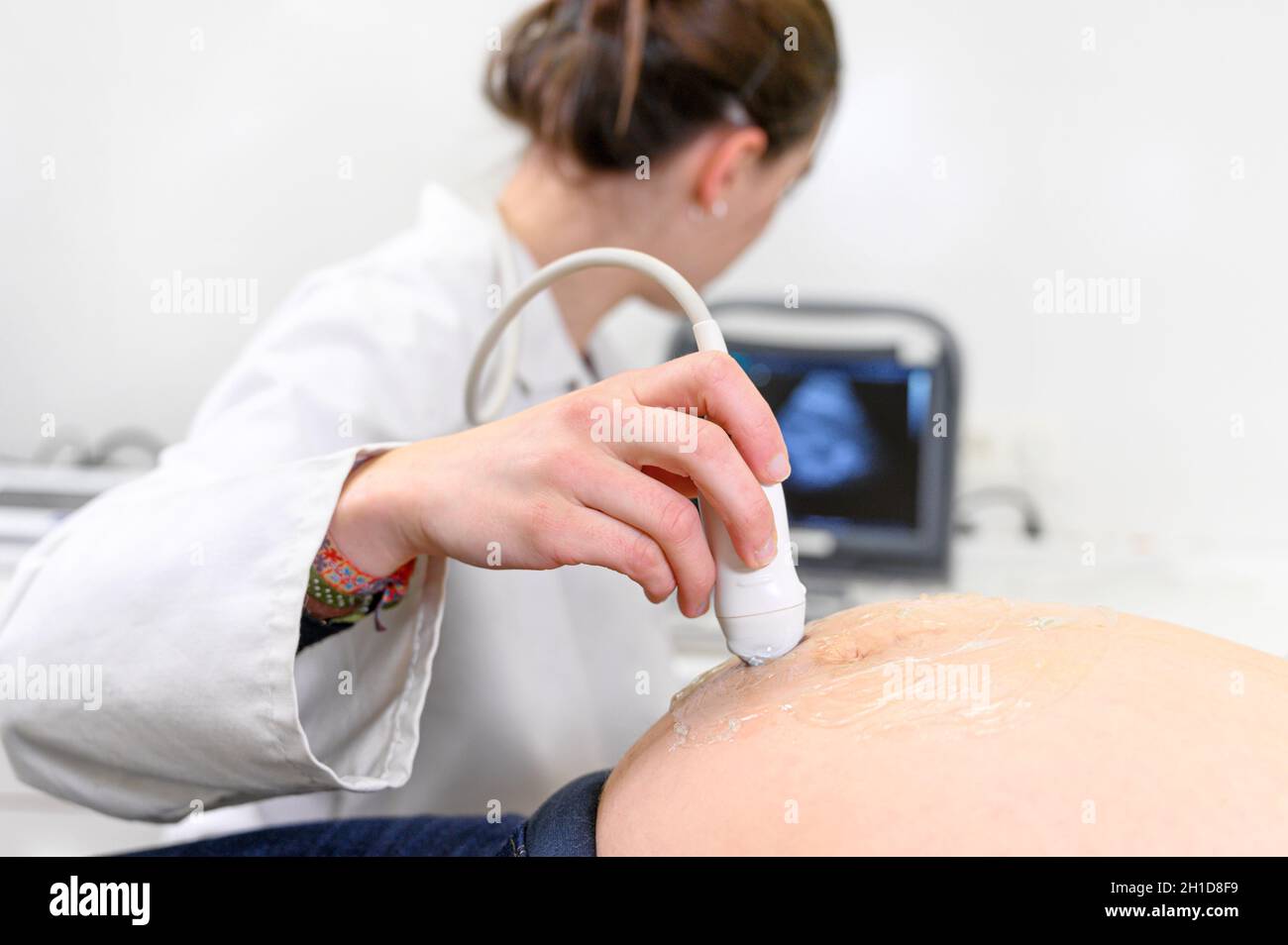 Il medico esegue la procedura ecografica o ecografica per una donna incinta in ospedale, primo piano del trasduttore mobile ostetrista sul ventaglio di Foto Stock
