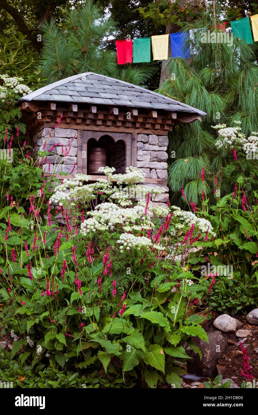 Giardino del 50° anniversario dei Trailfinders. Pietra, legno, e ardesia costruzione che ospita acqua-guidato ruota di preghiera. Pino Pinus wallachiana alle spalle, Persicaria Foto Stock