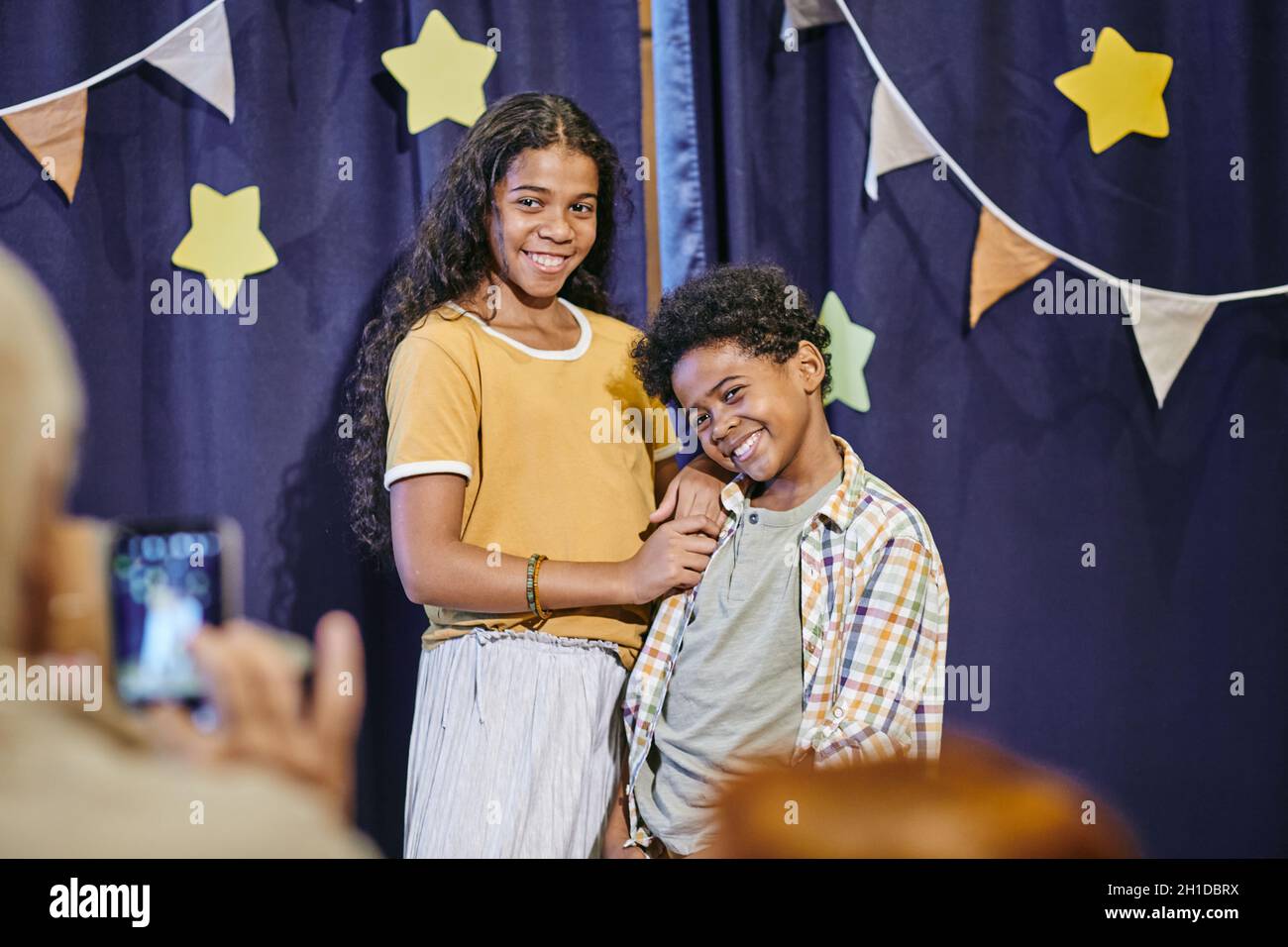 I bambini africani felici sorridono e posano alla macchina fotografica mentre gli adulti li fotografano dopo lo spettacolo Foto Stock