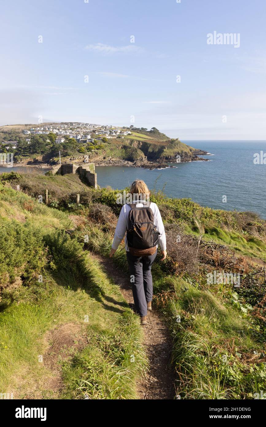 Una donna che cammina lungo il South West Coast Path, Cornovaglia, presso l'estuario di Fowey e il castello di St Catharines, Fowey, Cornovaglia UK Foto Stock