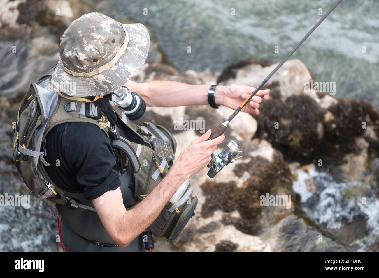 L'uomo la pesca nel fiume. fisher in acqua. fisherman Visualizza tecnica di pesca l'uso. Asta. hobby e attività sportiva . Foto Stock
