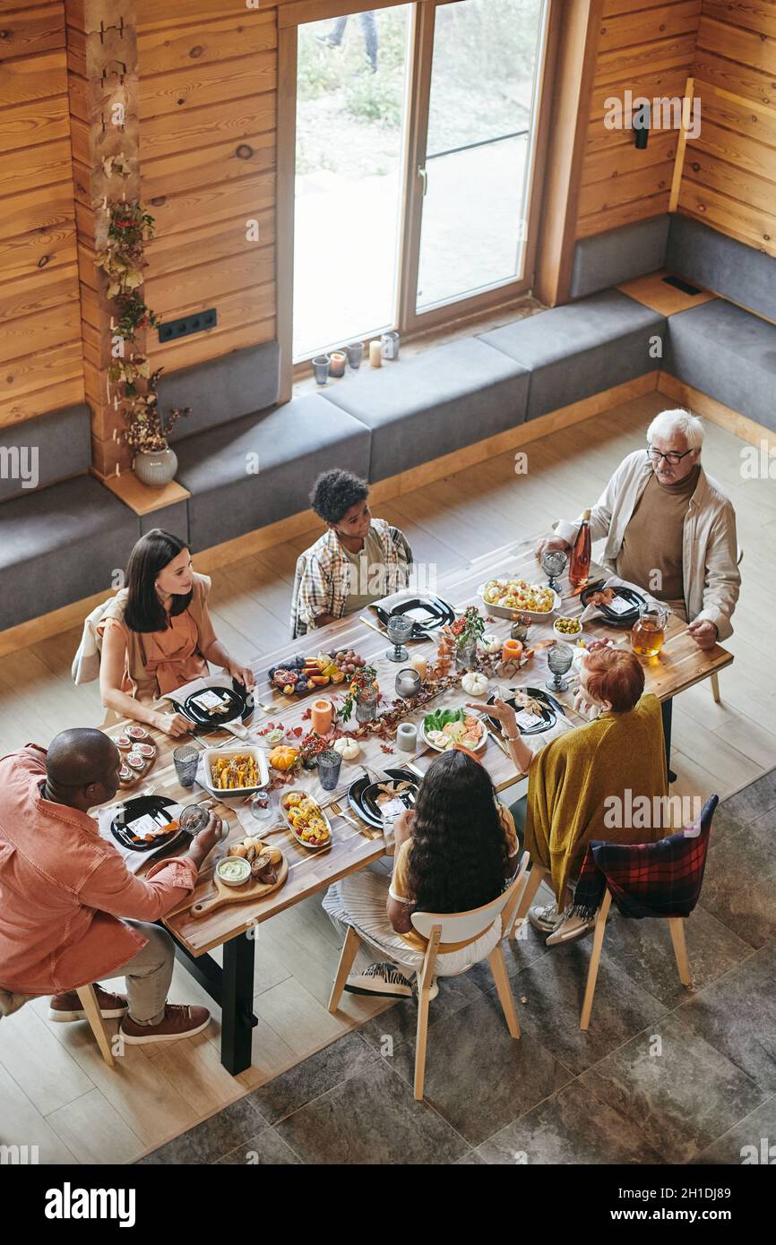 Vista ad alto angolo della famiglia che parla l'un l'altro durante la cena al tavolo da pranzo di casa Foto Stock