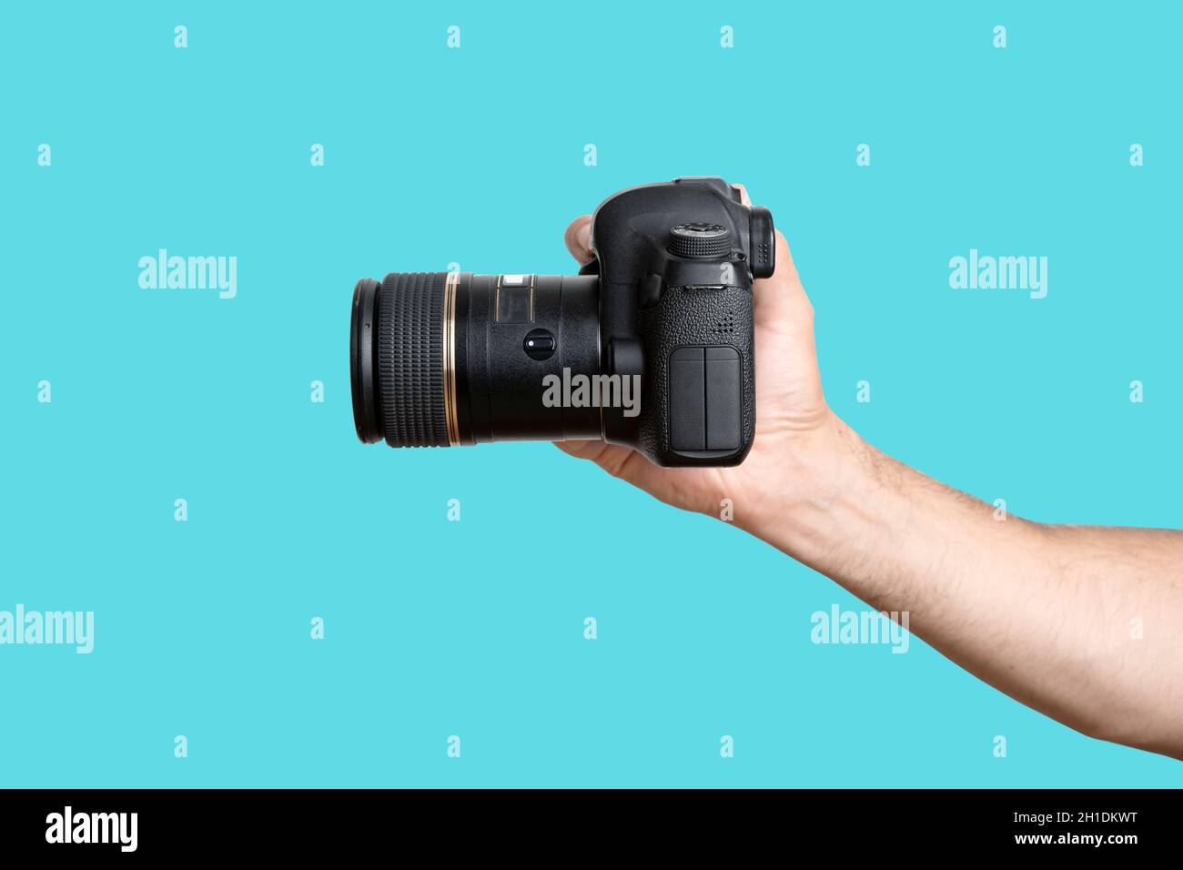 Mano con una fotocamera. Una mano che tiene una fotocamera reflex digitale su uno sfondo blu pulito. Foto di alta qualità Foto Stock