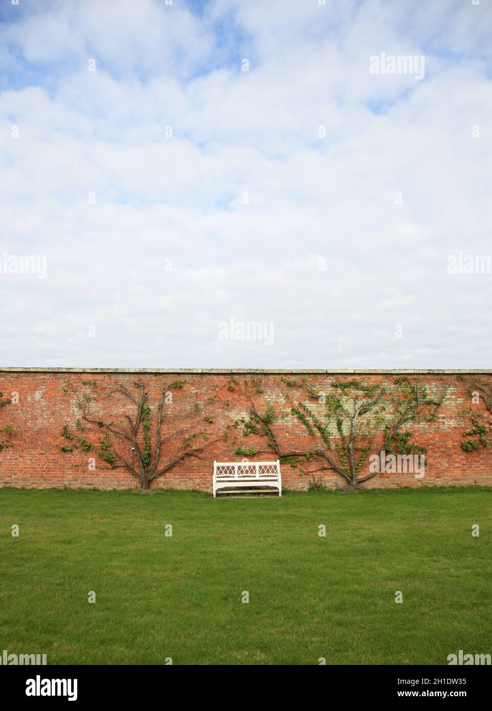 Panca bianca in un giardino murato inglese. Foto Stock