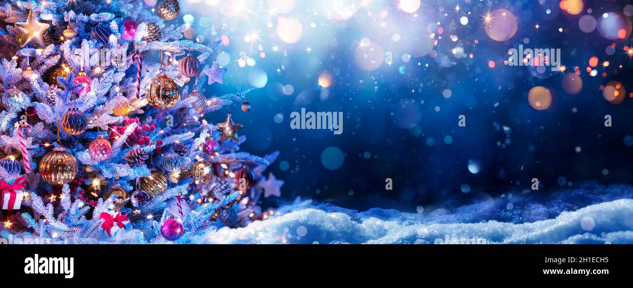 Albero di Natale sulla neve di notte - ornamento appeso con luci sfocate in sfondo astratto Foto Stock