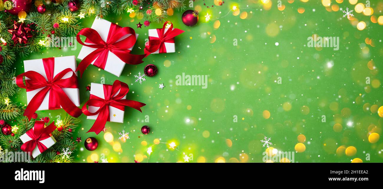 Confezioni regalo su Green con rami di abete e ornamento di Natale - regali con il nastro rosso e luci bokeh Foto Stock