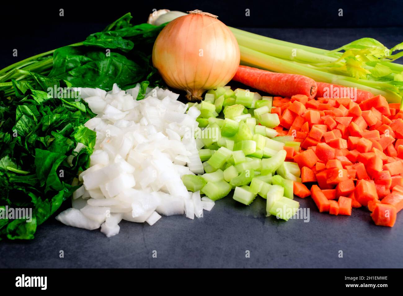 Spinaci tritati con cipolle a dadini, sedano e carote: Verdure tritate verdure intere sullo sfondo Foto Stock