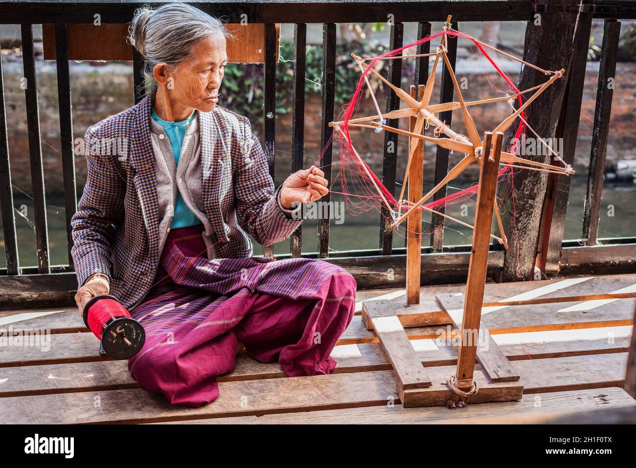 INLE LAKE, MYANMAR - 8 GENNAIO 2014: La donna birmana ruota filatura filato in fabbrica di tessitura dove il tessile è fabbricato in modo tradizionale Foto Stock