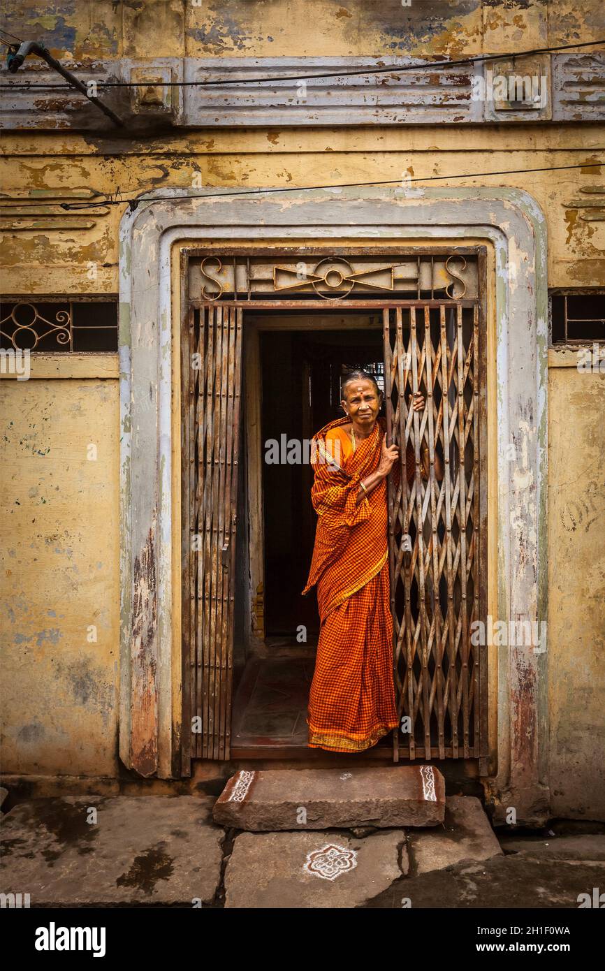 TIRUCHIRAPPALLI, INDIA - 15 FEBBRAIO 2013: Donna indiana non identificata in piedi all'ingresso della sua casa Foto Stock