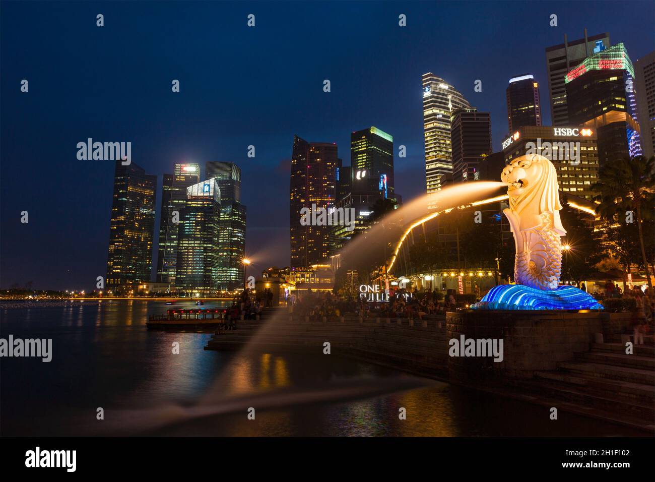 SINGAPORE - 1 GENNAIO 2014: Vista notturna di Singapore Merlion a Marina Bay contro lo skyline di Singapore. Merlion è una famosa icona turistica, mascotte e. Foto Stock