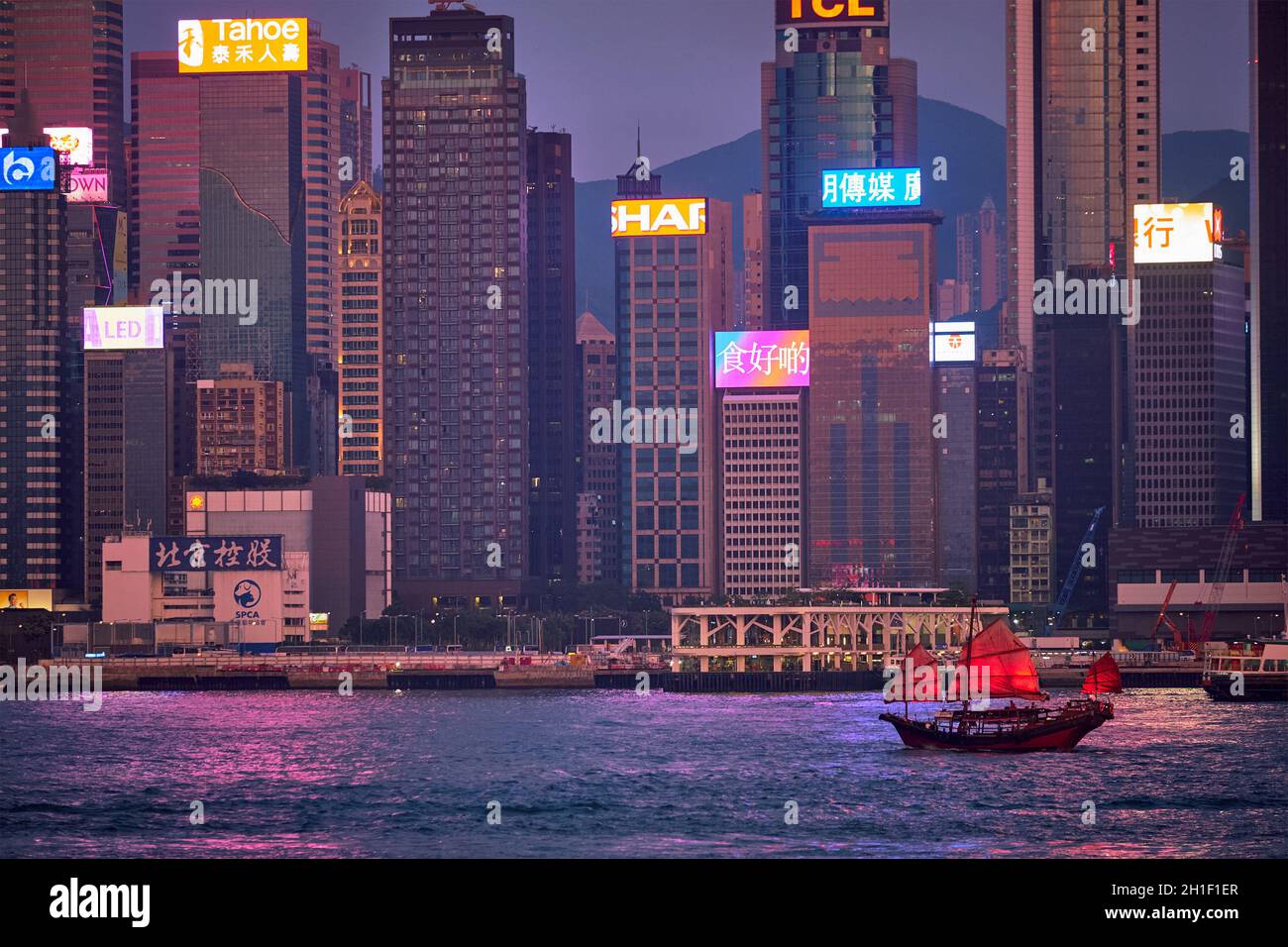 HONG KONG, CINA - 1 MAGGIO 2018: Traghetto turistico della spazzatura con vele rosse e skyline di Hong Kong skyline città grattacieli del centro città su Victoria Harbour in t Foto Stock