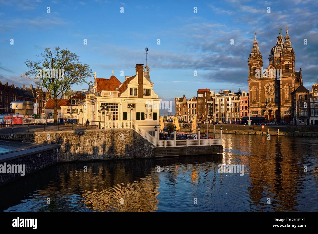 AMSTERDAM, PAESI BASSI - 9 MAGGIO 2017: Centro informazioni turistiche, canale di Amsterdam e Chiesa di San Nicola (Sint-Nicolaaskerk) al tramonto. Amsterd Foto Stock